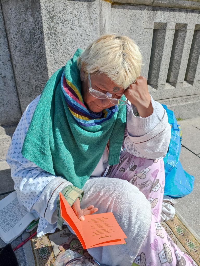 Eine wohnungslose Frau liest eine Osterkarte mit einer Brille